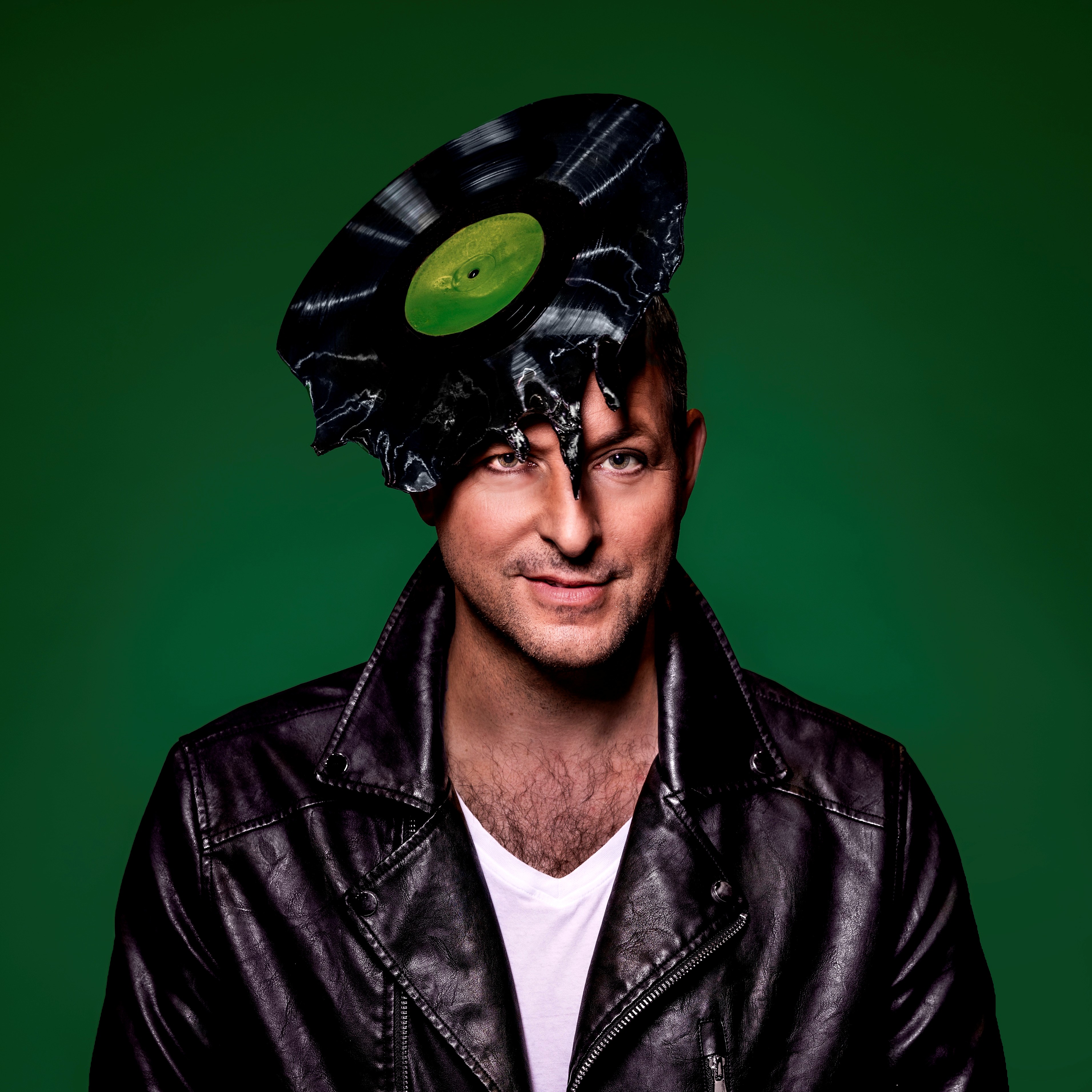 Plakatmotiv Heirat‘ mich ein bisschen, FOto: Jochen Quast Kristian Lucas mit schwarzer Schallplatten-Kopfbedeckung und schwarzer Lederjacke vor grünem Hintergrund.