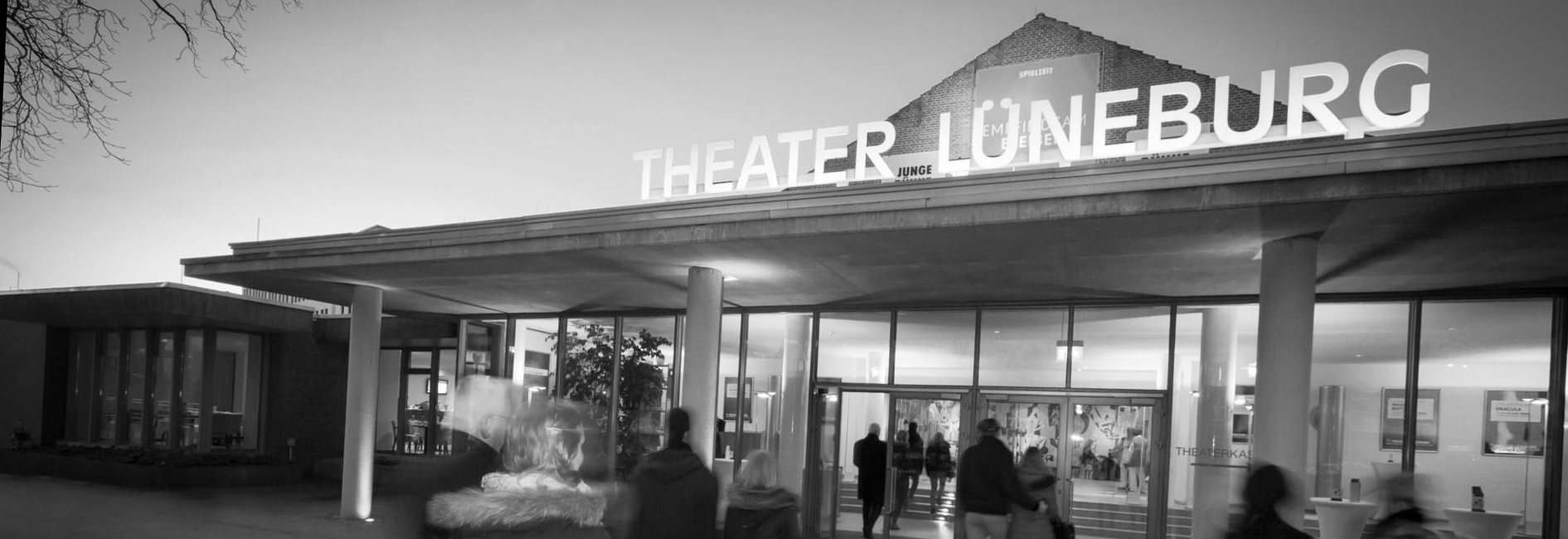 Eingang des Theaters Lüneburg bei Abenddämmerung mit beleuchtetem Schriftzug