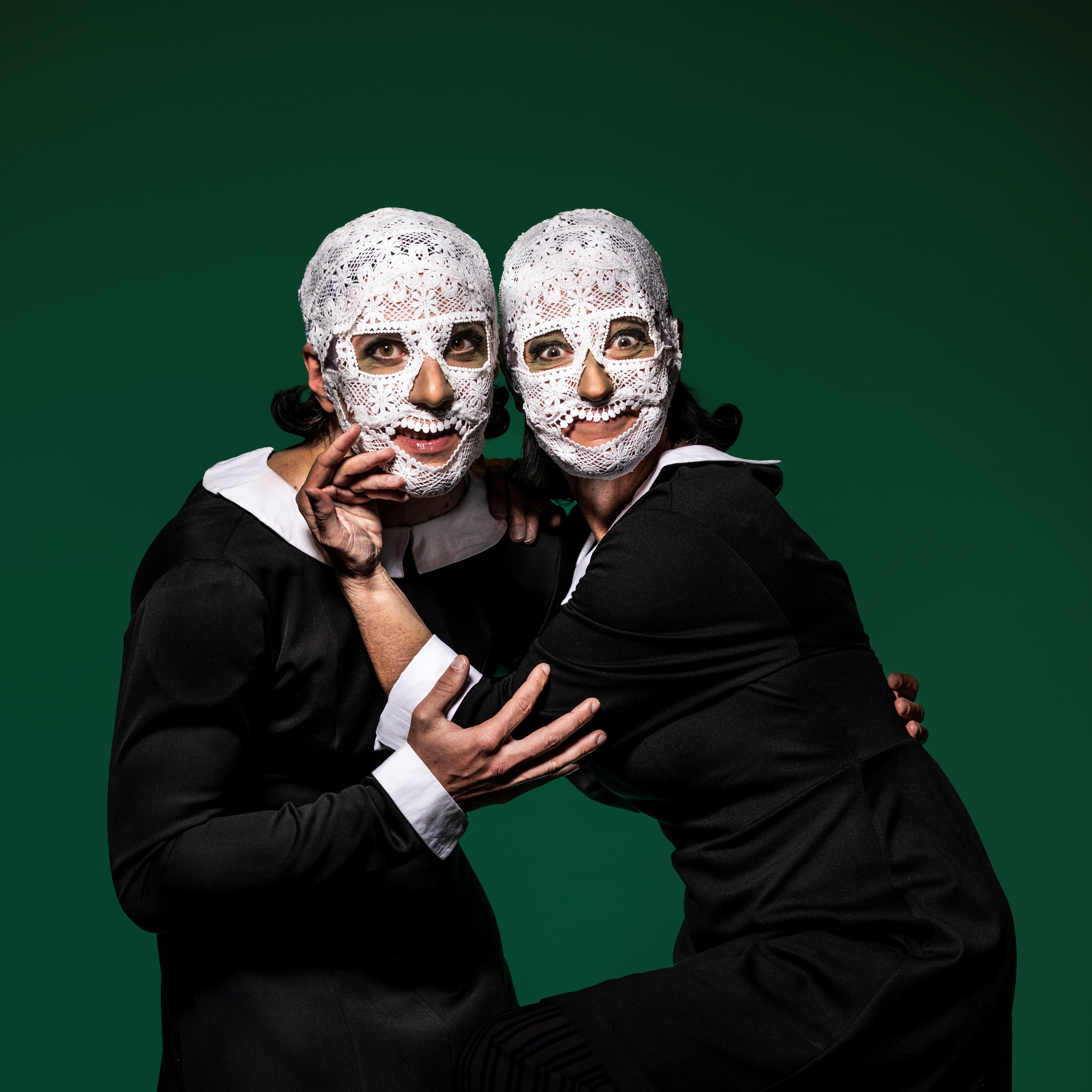 Plakatmotiv Arsen und Spitzenhäubchen, Foto: Jochen Quast Zwei Personen (Christoph Vetter und Britta Focht) in schwarzen Kostümen mit weißen Spitzen-Totenkopfmasken posieren eng umschlungen vor grünem Hintergrund.; Foto: Jochen Quast