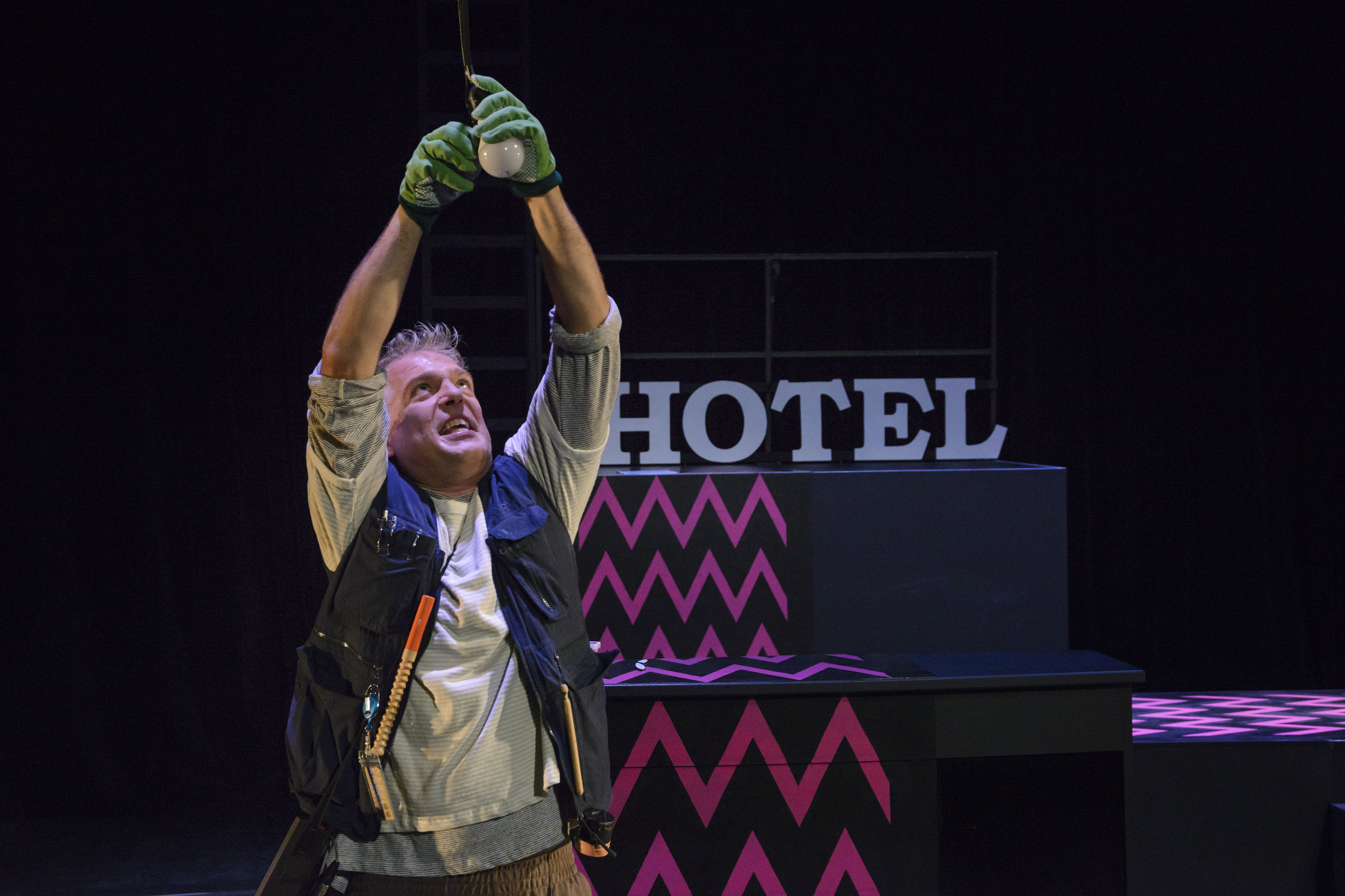 Hotel Lauter und die Unsichtbaren | Schauspiel von Armela Madreiter | 8+ | Foto: Nicolai Stephan | Gregor Müller als Elin hat Arbeitshandschuhe an und tauscht eine Birne an der Decke aus